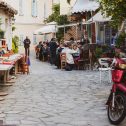 Athens, Greece - Mar 28, 2016: Tiny cute Greek street with people enjoying food on the terrace cafe in cozy vintage neighborhood